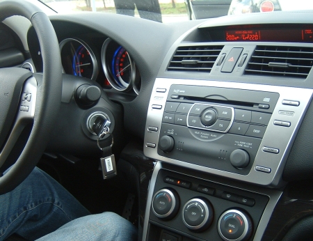 Az új Mazda6 műszerfala. Hazánban a navigáció csak a gyári összeszerelés után utólag beépítettként rendelhető, a legmagasabb felszereltségi fokozatnak sem része. Cégünk érintőképernyős Dupla DIN méretű egységgel tudja ezt orvosolni, mely DVD filmek lejátszására is alkalmas. 