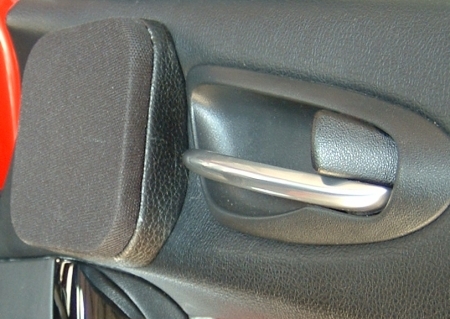 Fekete hangszóróselyem bevont fedél alatt rejtőzködik a Focal szett középsugárzója az egyedi konzolon, a Mazda RX-8 ajtaján.