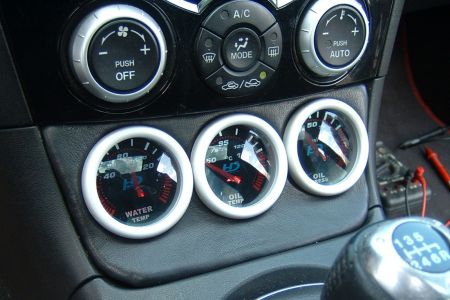 Mazda RX-8-ban a hamutartó helyére beépített vízhőfok, olajhőmérséklet, olajnyomás órák.